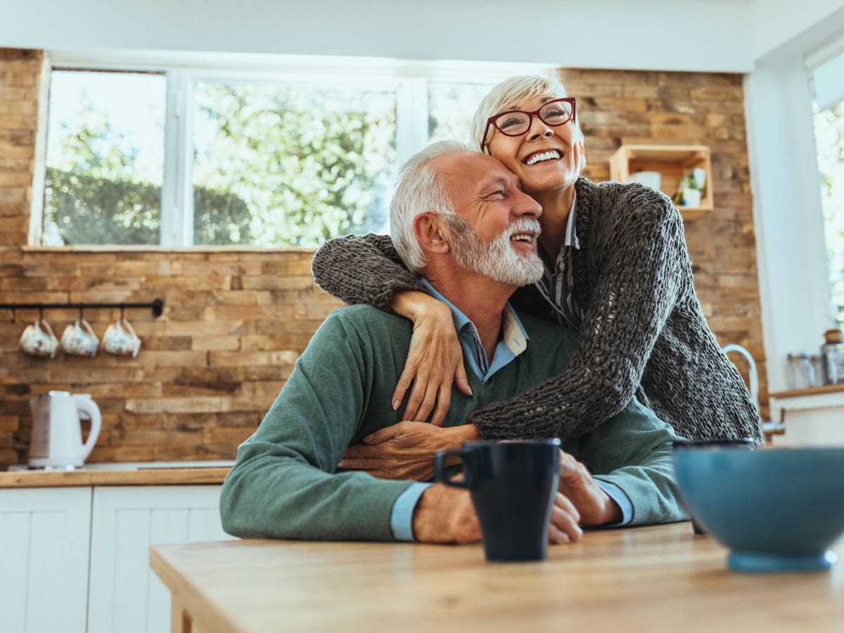 A man and woman sitting at the table hugging.