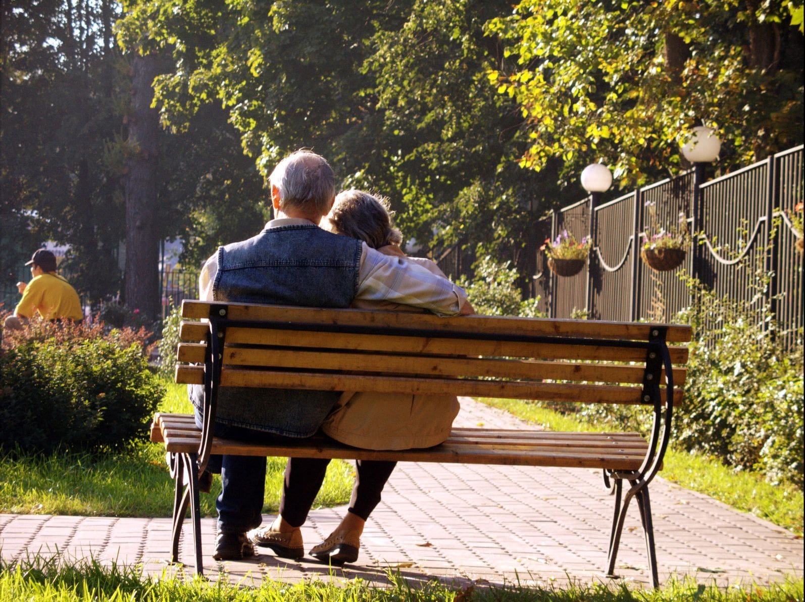 A couple of people sitting on top of a wooden bench.